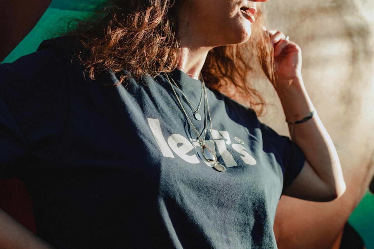 Stylish woman in a black graphic tee and necklaces, outdoors in natural light.