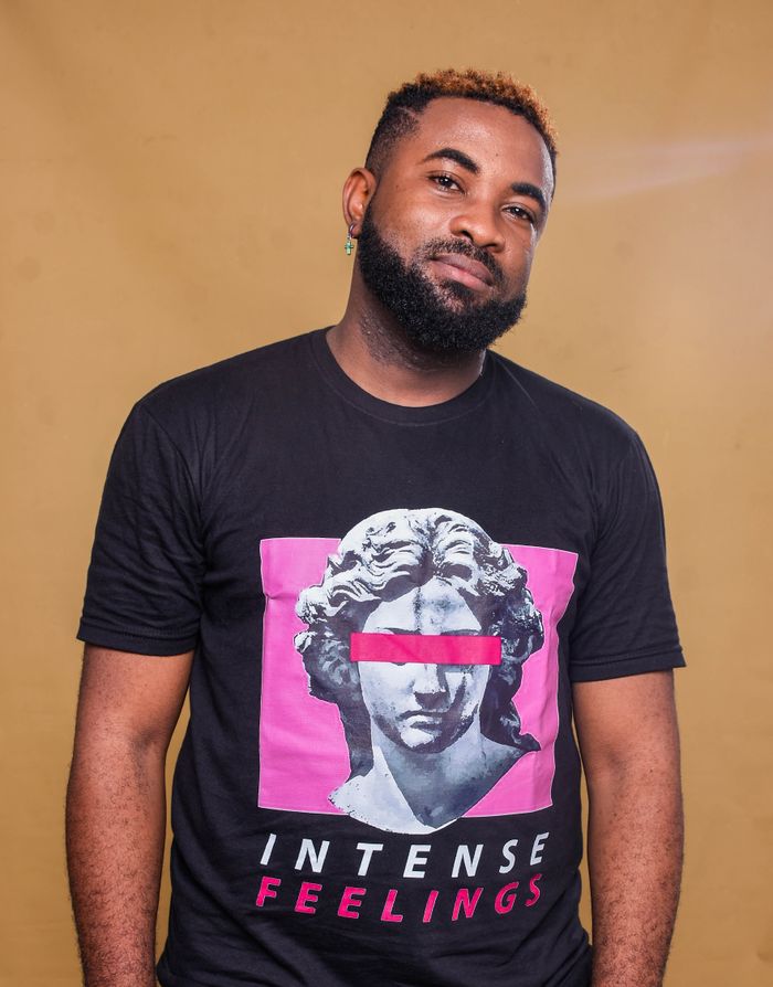 who-we-are African American man standing confidently in a graphic T-shirt with artistic design.