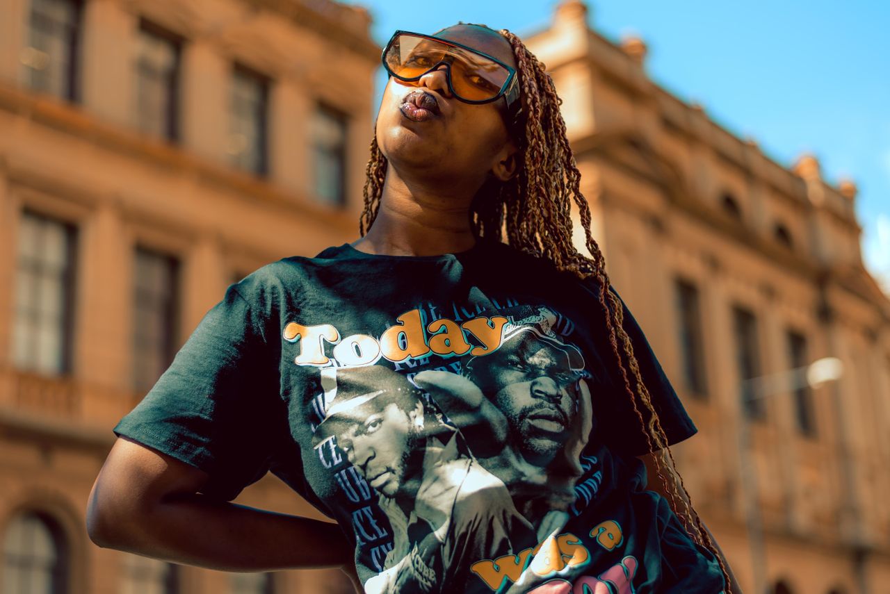 Fashion-forward woman with sunglasses and graphic tee in urban Pretoria setting.
